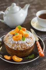 simple butter cake decorated with slices of apricots on a dark wooden background