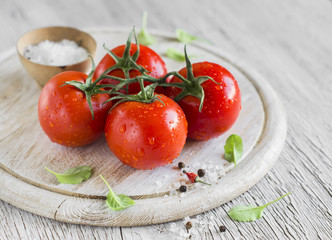fresh tomatoes on a branch on a light wooden background