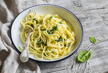 pasta with spinach and cream sauce on vintage enameled plate on a light wooden background