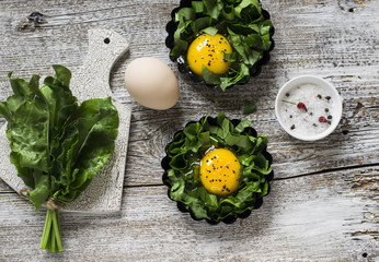 Obraz na płótnie Canvas fresh sorrel and eggs on a light wooden background, ingredients for making baked eggs