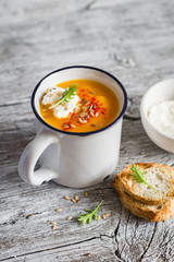 pumpkin soup with paprika in ceramic mugs on a light wooden background