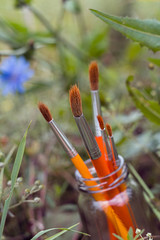 Paintbrushes in bank on a background of grass