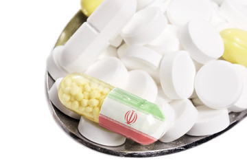 Spoon full of pills and a capsule with the flagdesign of Iran.(s