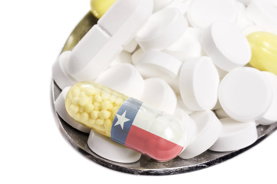 Spoon full of pills and a capsule with the flagdesign of Texas.(
