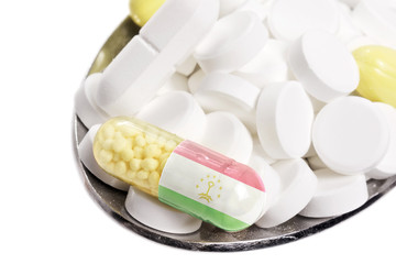 Spoon full of pills and a capsule with the flagdesign of Tajikis