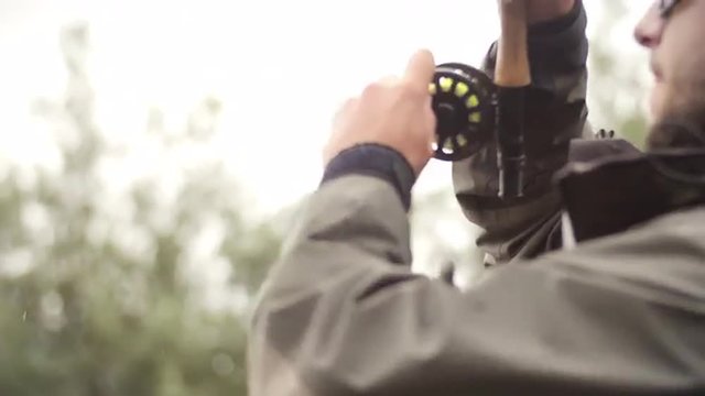 Man Reeling In A Fish From A River