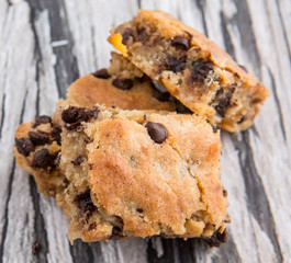 Sweet brownie dessert bar with chocolate chips over wooden background