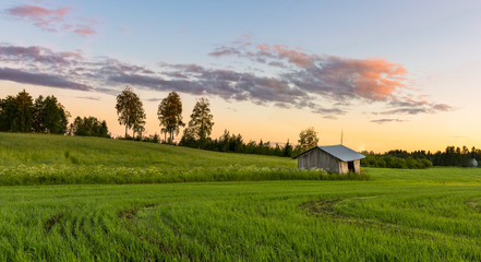 Cloudy sky reflecting from river running through green fields and grass.