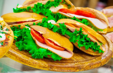 Ham, tomatoes sandwiches and lettuce leaves on a show-window of shop