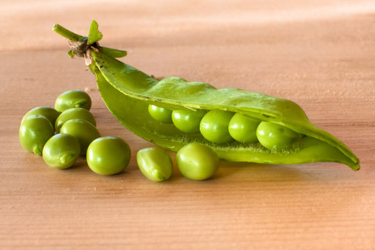 opened green pea pod on the wooden table