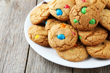 Cookies with colorful candy on plate on grey wooden background
