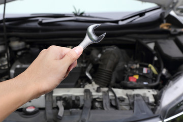 hand with wrench on car engine