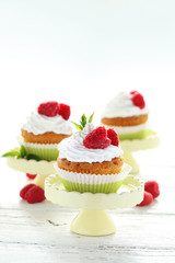 Raspberry cupcakes on cake stand on white wooden background