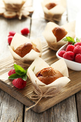 Fresh cupcakes with raspberries on grey wooden background