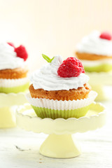 Raspberry cupcakes on cake stand on white wooden background