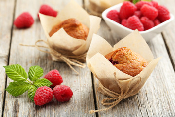 Fresh cupcakes with raspberries on grey wooden background