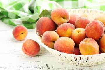 Ripe peaches fruit in basket on a white wooden background