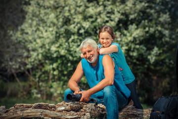 Grandfather with his granddaughter travel at attractive places. Old man photographer on a camping trip with his granddaughter.