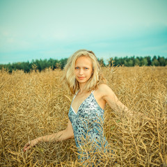 beautiful blonde walks into the field. portrait of a beautiful blonde in a field in spring