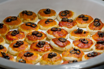 round meat pies with topping black olive sliced on buffet line
