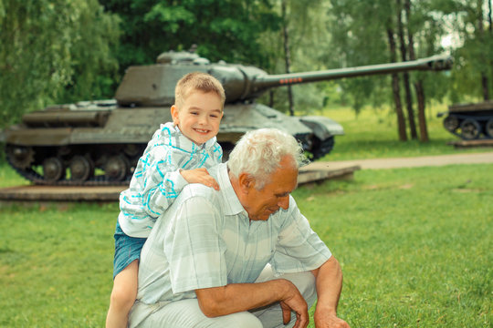 Grandfather and grandson are photographed on a background of vintage tank