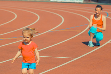 Mother & little daughter running around the stadium. Child runs away from mom at the stadium.