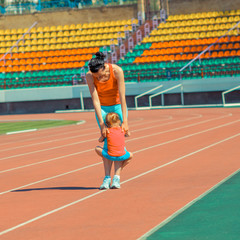 Obraz premium Mother & little daughter running around the stadium. Child runs away from mom at the stadium.