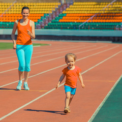 Mother & little daughter running around the stadium. Child runs away from mom at the stadium.