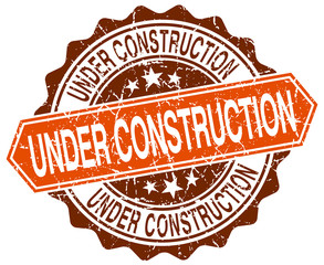 under construction orange round grunge stamp on white