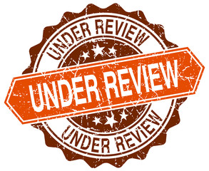 under review orange round grunge stamp on white