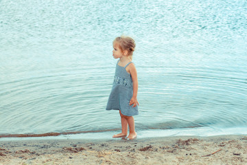 beautiful little girl child playing in the sand on the shore