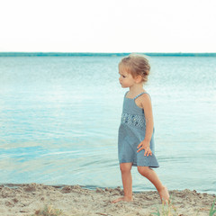 beautiful little girl child playing in the sand on the shore