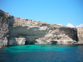 Rocky coast and transparent, cyan waters of the Blue Lagoon on the island of Comino, Malta, on a sunny summer day.