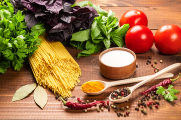 Raw pasta, vegetables, basil and spices on the wood table