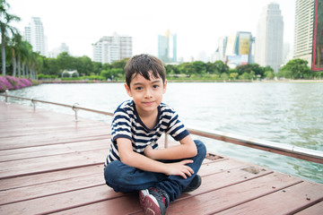 Little boy sitting nearby the lagoon in the pard