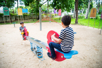 Little boys playing seesaw together in the park