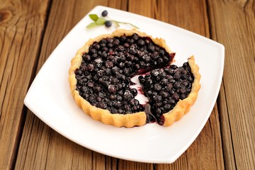 Homemade tart with whole wild blueberries cut in square white pl