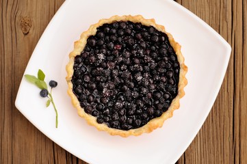 Homemade tart with whole wild blueberries in square white plate