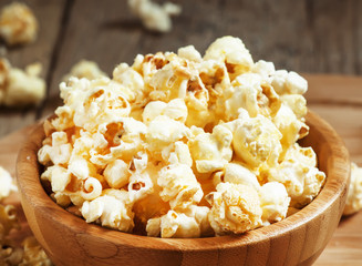 Sweet caramel popcorn in a wooden bowl, selective focus