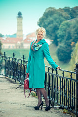 Beautiful mature blonde in  coat posing in the park. Portrait of a senior woman outdoors.