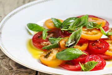 Vegetable salad of colorful tomatoes and basil with olive oil an