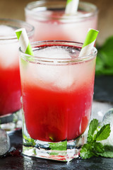 Cold red cocktail with ice and mint on a dark background, select
