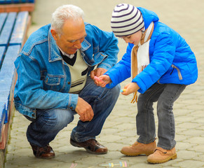 Grandfather and grandson draw with chalk on the road