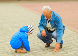 Grandfather and grandson draw with chalk on the road © ruslimonchyk