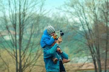 Grandfather teaches his grandson to photograph vintage camera. Grandfather and grandchild.