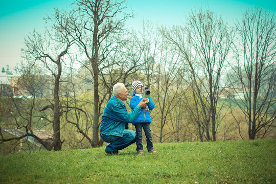 Grandfather teaches his grandson to photograph vintage camera. Grandfather and grandchild.