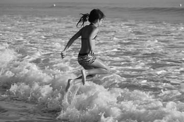 Jeune fille sautant les vagues