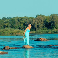 Mature beautiful blonde in blue dress enjoying the sea