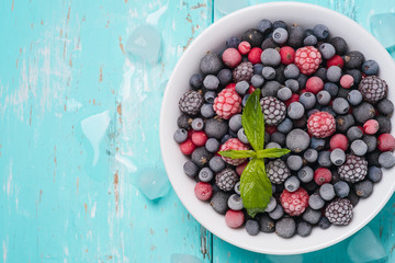 Frozen berries on a turquoise background with space for text, to
