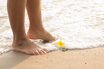 Girl standing on the beach with her bare foot.